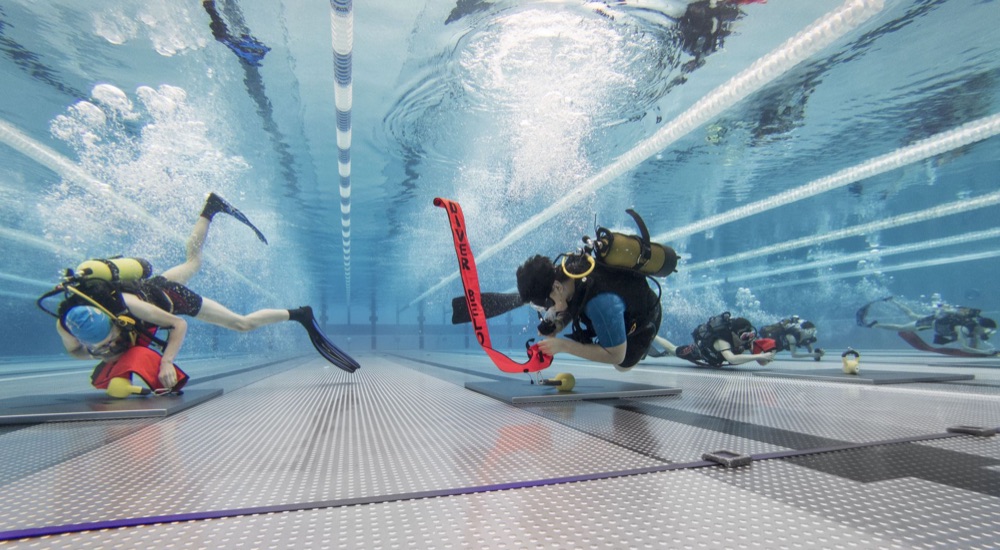 Plongeurs en piscine réalisant un parcours d'adresse avec bouteille